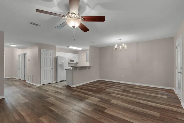 a view of kitchen and empty room with wooden floor