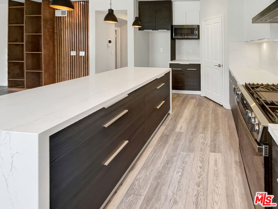 125 Lakeside Drive Buena Park, CA 90621 - Photo 31 of 57 a kitchen with kitchen island wooden cabinets and a stove top oven