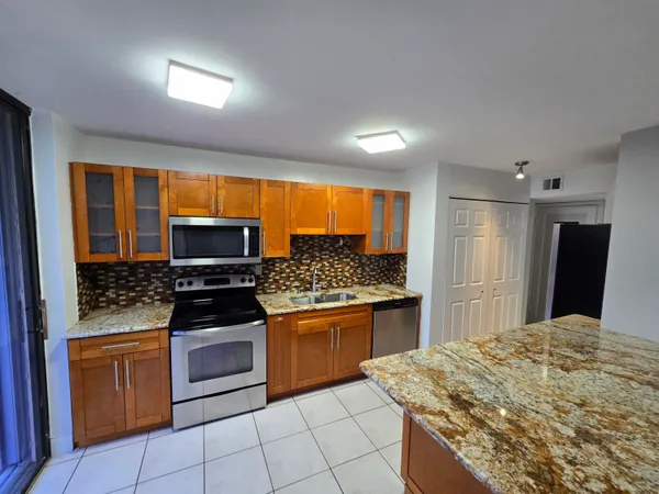 a kitchen with granite countertop a stove a sink and a refrigerator