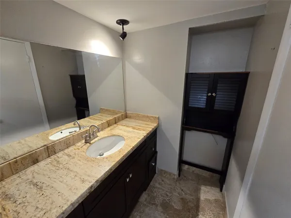 a bathroom with a granite countertop sink and a toilet