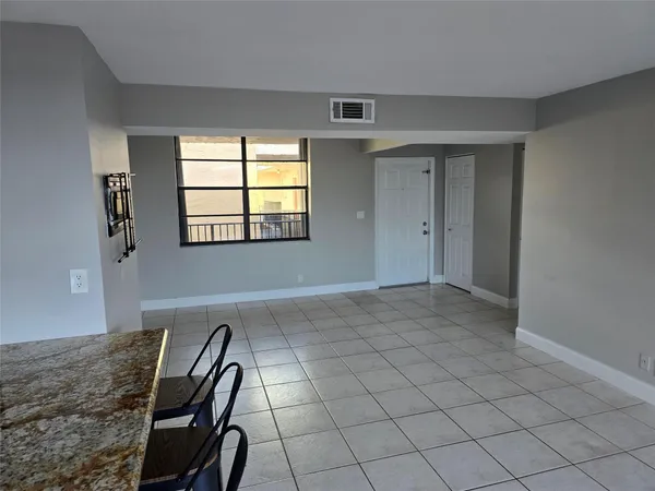 a view of an empty room with wooden floor and windows