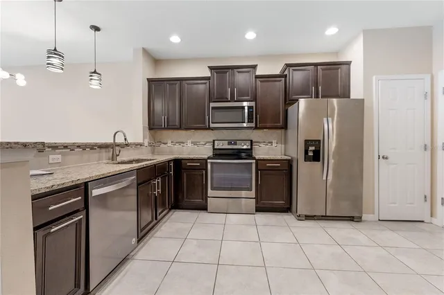 a kitchen with stainless steel appliances granite countertop a refrigerator a stove a sink and a microwave