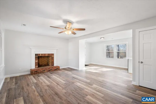 a view of an empty room with a window and a kitchen