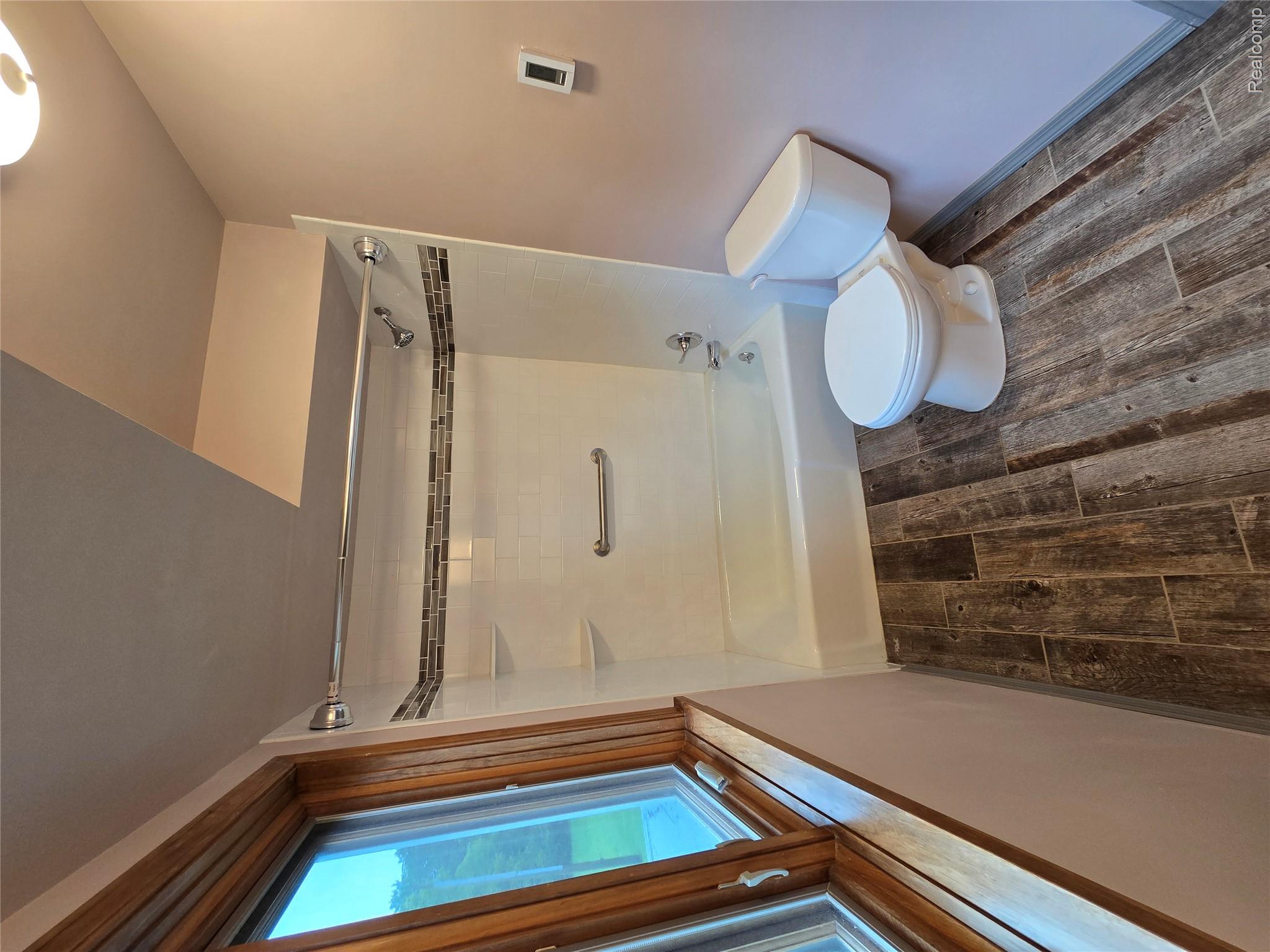 5282 McIntyre Road North Street, MI 48049 - Photo 41 of 53 Bathroom featuring a white bathtub, decorative tile accent, wood-finish tile flooring, and a window with wood trim