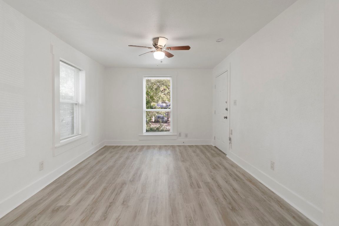 1606 Maple Avenue Austin, TX 78702 - Photo 5 of 15 an empty room with wooden floor chandelier fan and windows
