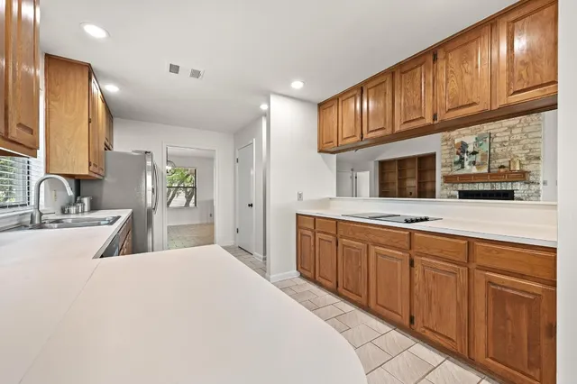a large kitchen with kitchen island granite countertop a sink stainless steel appliances wooden cabinets and a counter top space