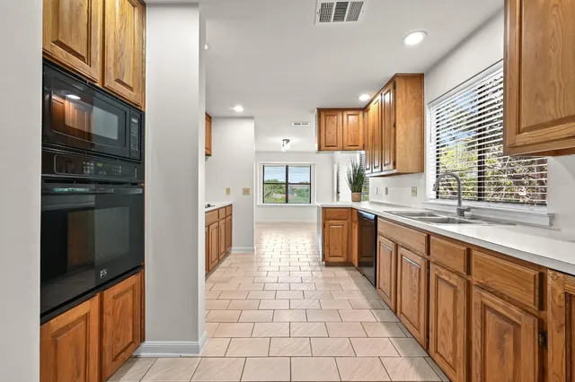 a large kitchen with stainless steel appliances granite countertop a refrigerator and a sink