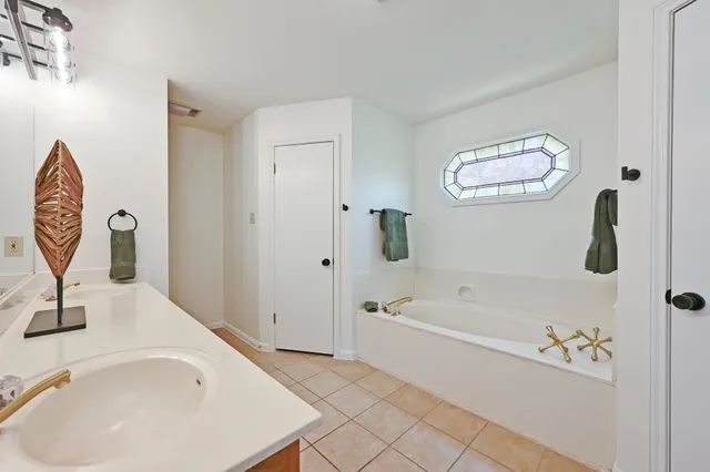 a bathroom with a tub a sink and a mirror