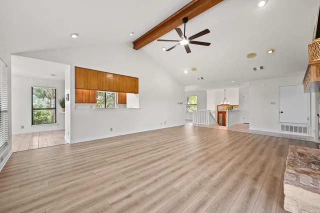 a view of empty room with wooden floor and fan