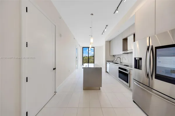 a large kitchen with stainless steel appliances a sink dishwasher a stove and white cabinets