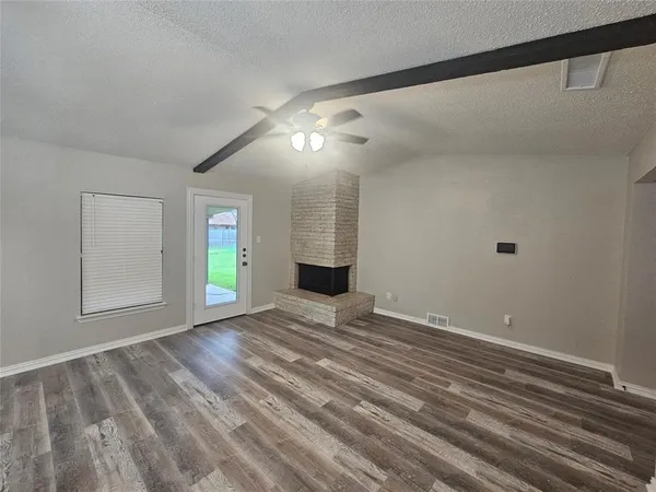 a view of an empty room with window and wooden floor
