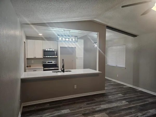 a room with kitchen island a sink and wooden floor