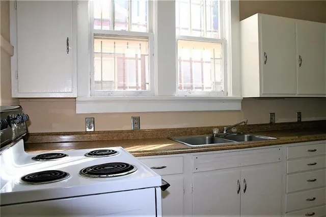 a kitchen with sink a stove and white cabinets