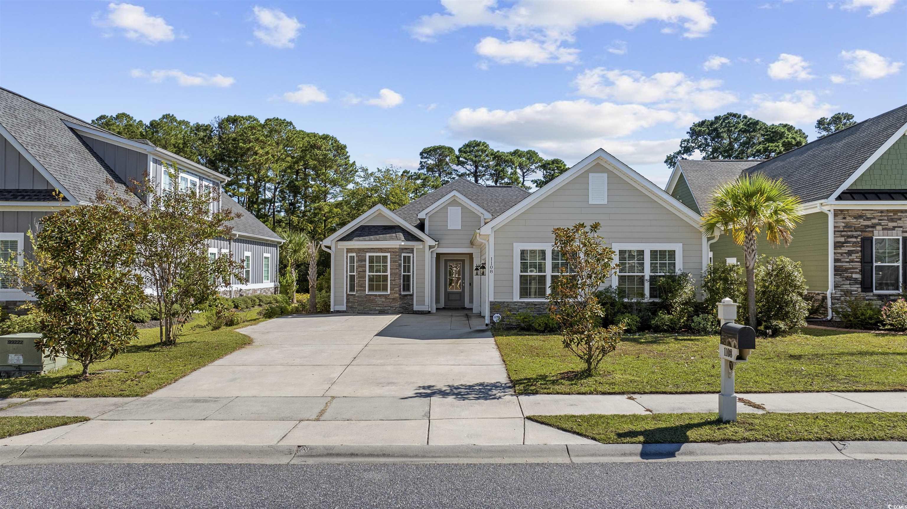 View of front of house featuring a front lawn, stone siding, and driveway