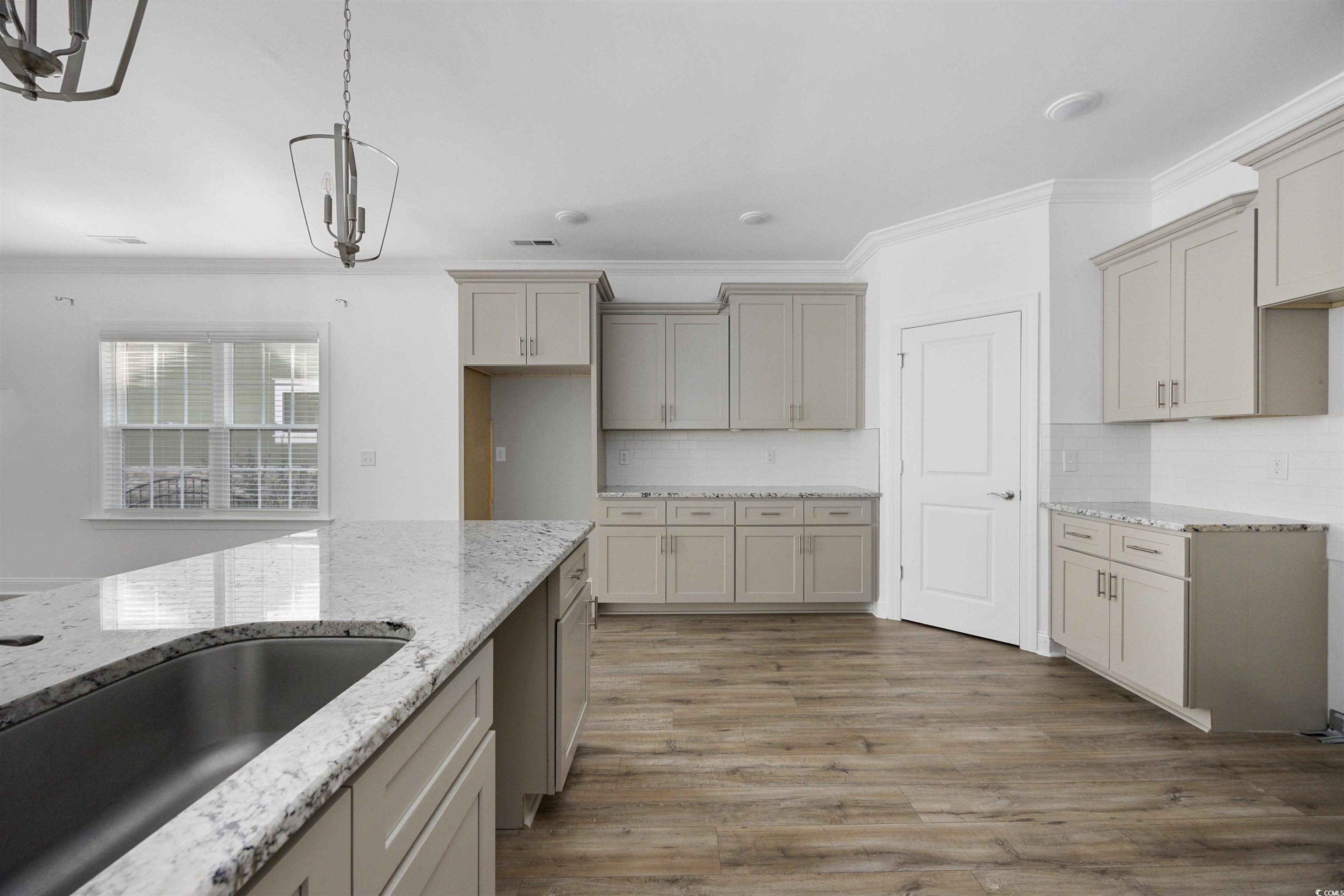 1108 Pochard Drive Conway, SC 29526 - Photo 14 of 37 Kitchen with light stone counters, crown molding, light wood-type flooring, decorative backsplash, and pendant lighting