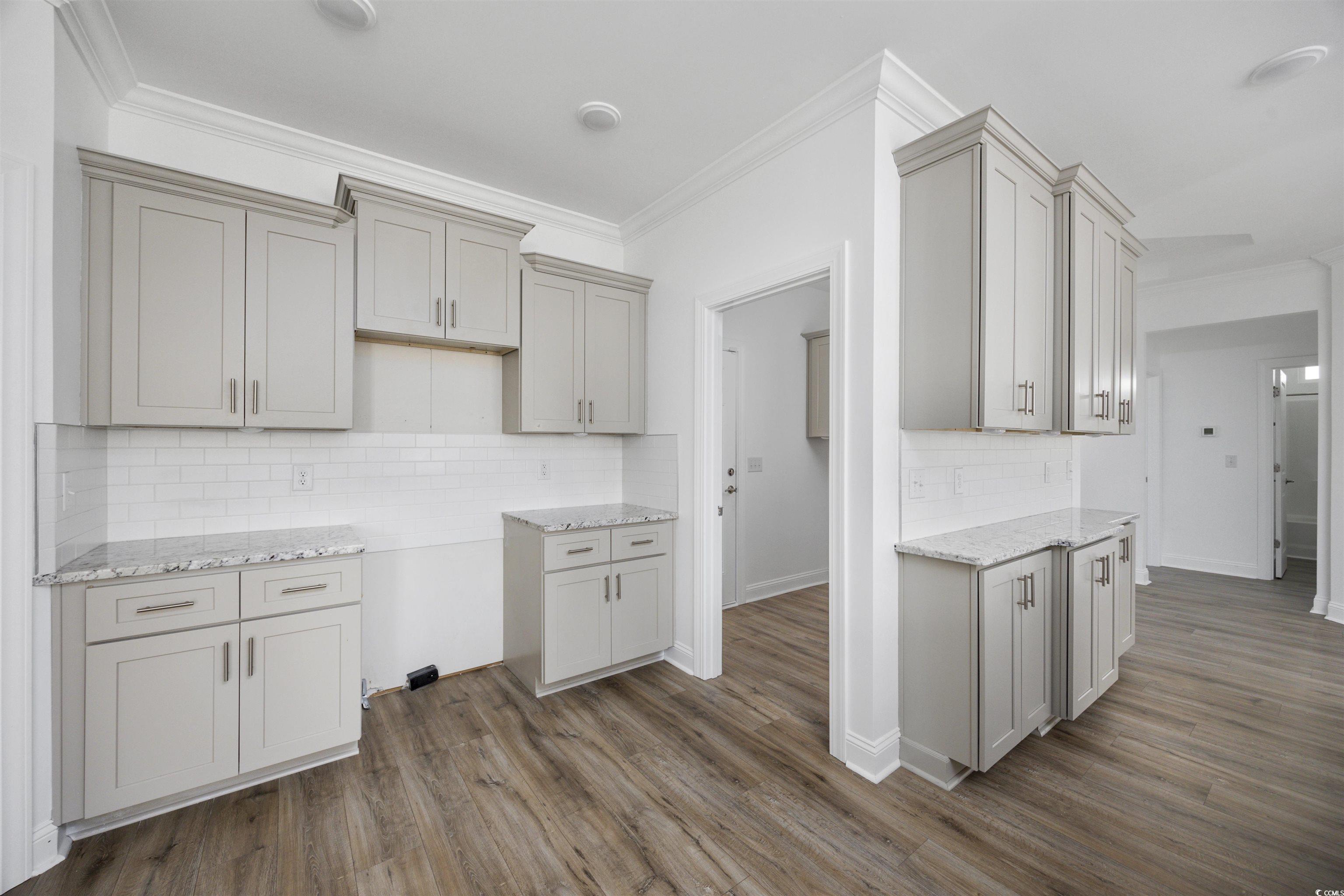 1108 Pochard Drive Conway, SC 29526 - Photo 15 of 37 Kitchen with ornamental molding, decorative backsplash, dark wood finished floors, light stone countertops, and gray cabinetry