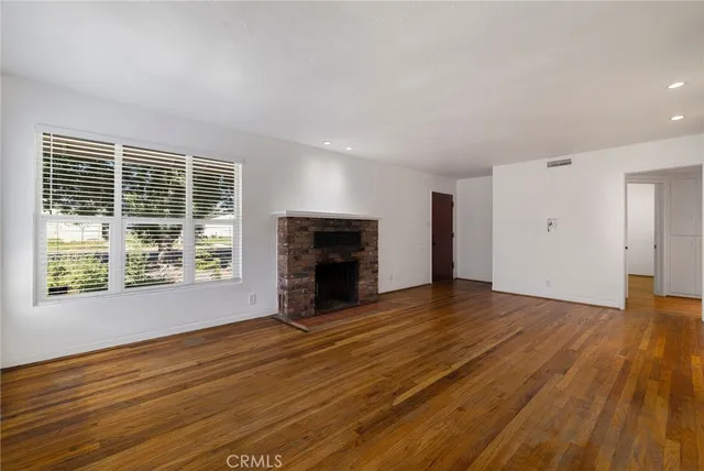 a view of an empty room with wooden floor and a fireplace