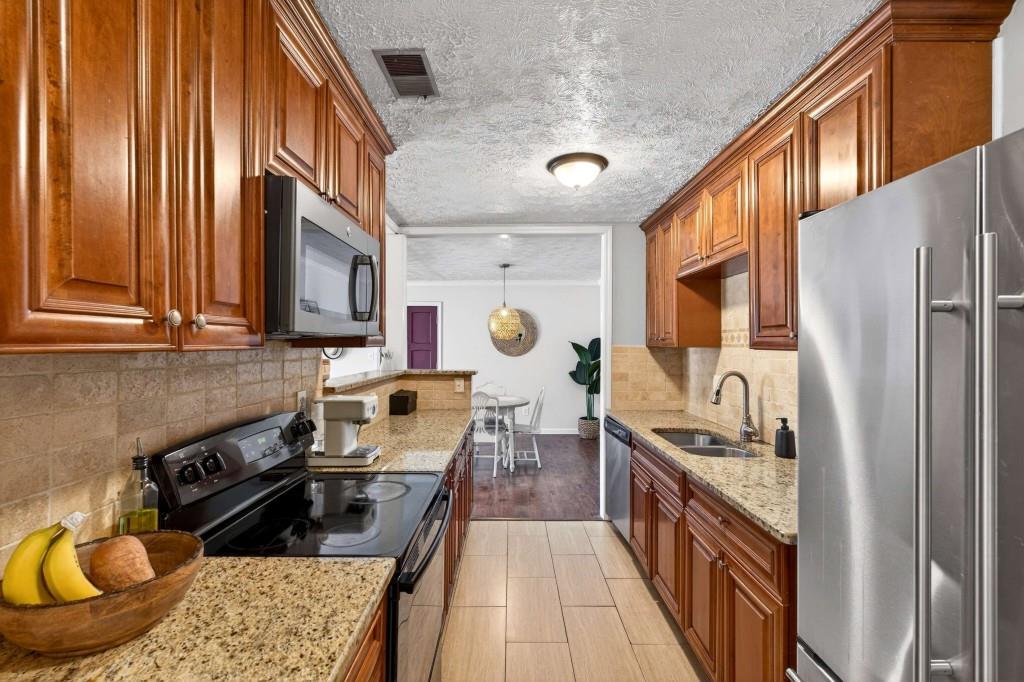 725 Dalrymple Road, Unit 5F Sandy Springs, GA 30328 - Photo 13 of 33 a kitchen with stainless steel appliances granite countertop a refrigerator a stove and a sink with wooden cabinets