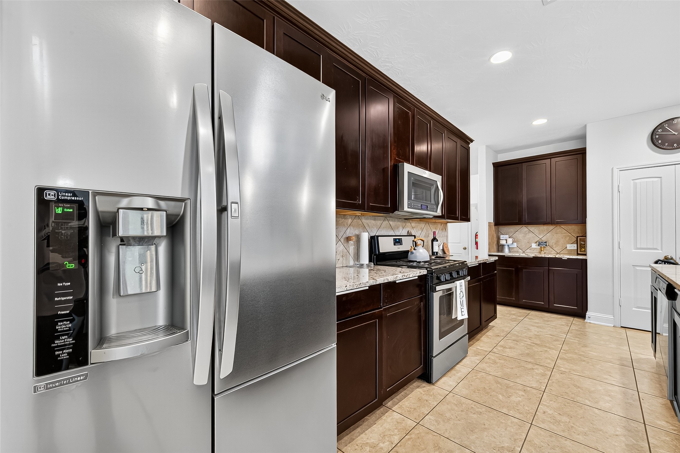 8107 Lockridge Terrace Lane Cypress, TX 77433 - Photo 20 of 50 This view highlights the sleek stainless steel refrigerator—included with the home—perfectly complementing the rich cabinetry and granite countertops. A functional and beautiful kitchen setup where style meets convenience, ready for your next culinary adventure.