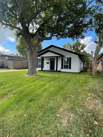 a white house that has a tree in front of a house