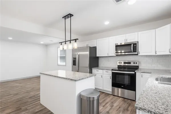 a kitchen with stainless steel appliances kitchen island granite countertop a stove a sink and a refrigerator