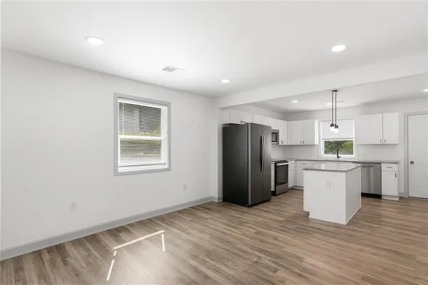 a view of a kitchen with refrigerator and wooden floor