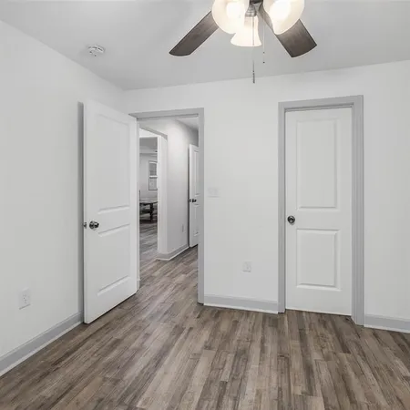 an empty room with wooden floor a chandelier fan and closet area