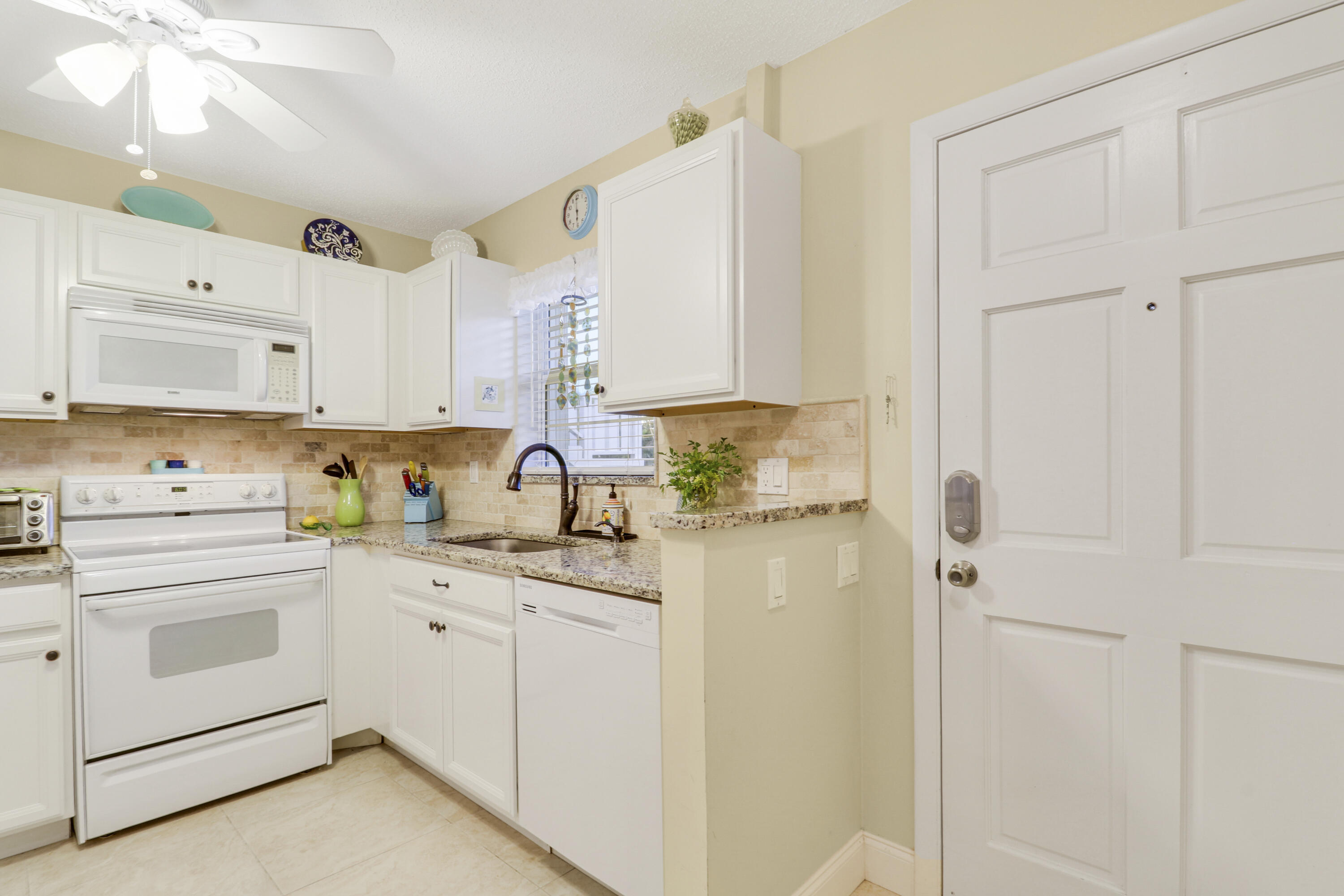 2929 Southeast Ocean Boulevard, Unit 1122 Stuart, FL 34996 - Photo 13 of 37 a kitchen with white cabinets and white appliances