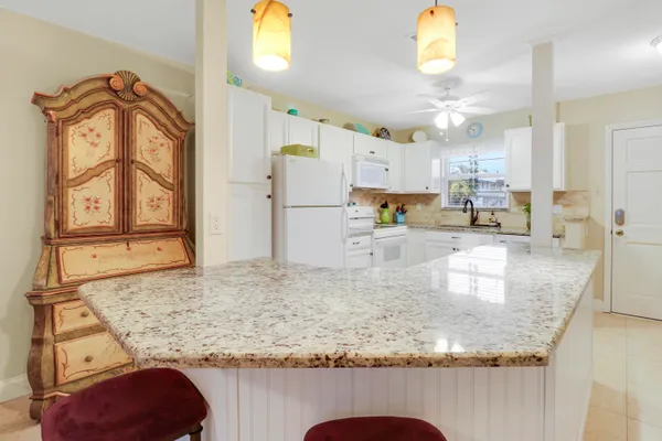 a kitchen with kitchen island granite countertop a sink a stove and a refrigerator