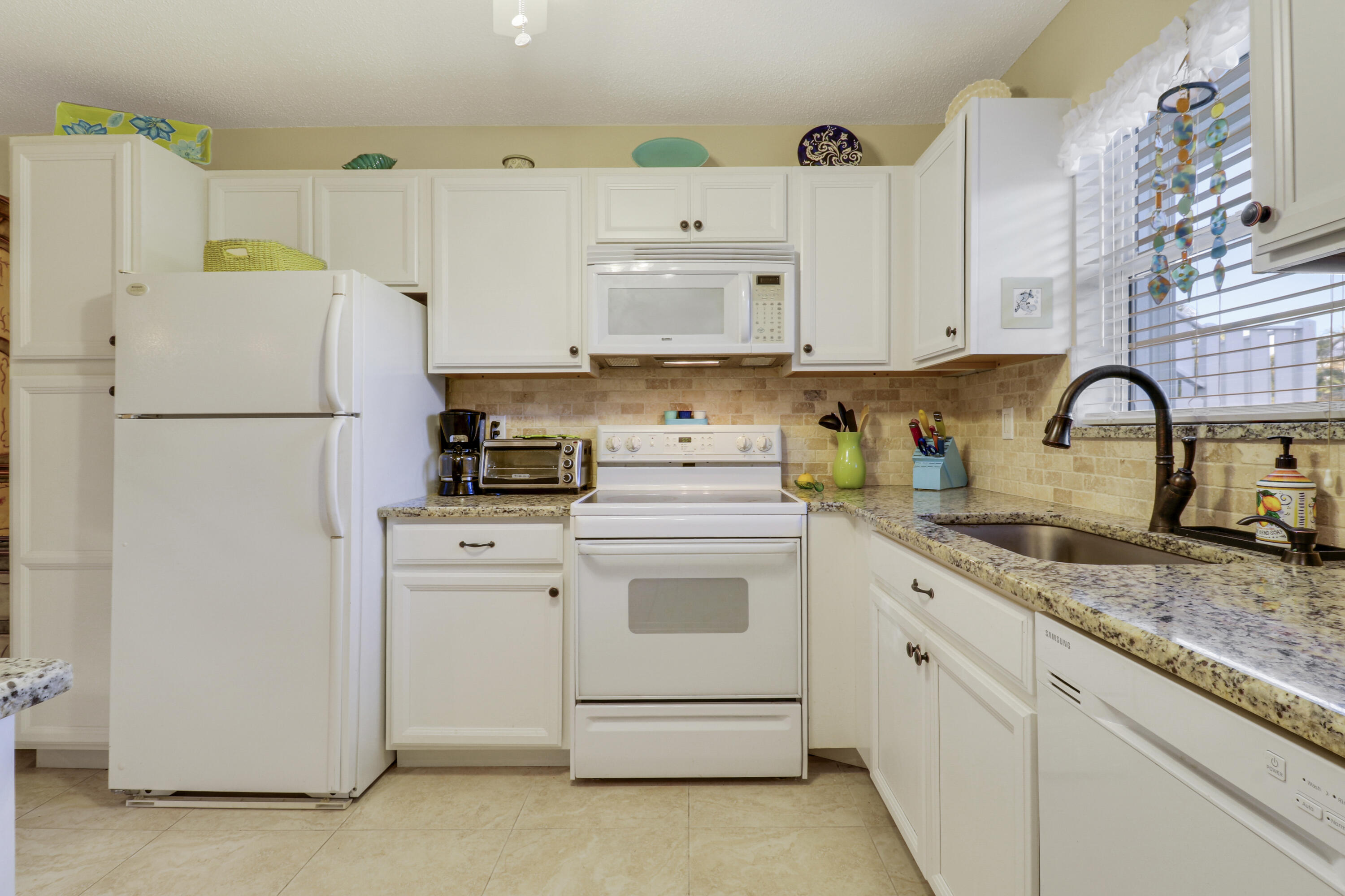 2929 Southeast Ocean Boulevard, Unit 1122 Stuart, FL 34996 - Photo 9 of 37 a kitchen with a white cabinets and white appliances