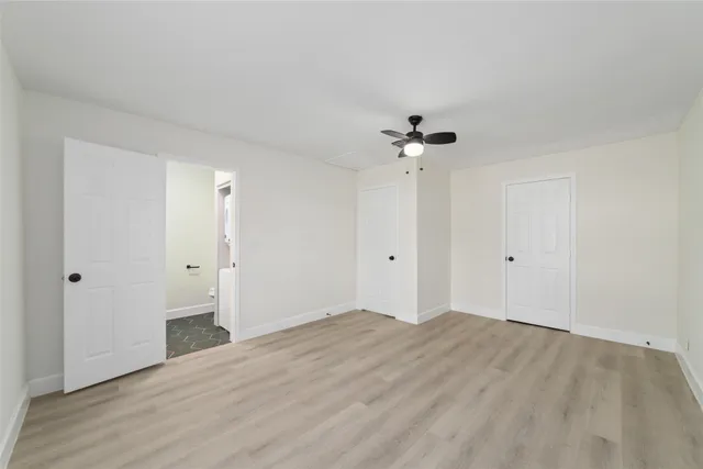 a view of an empty room with chandelier fan and wooden floor