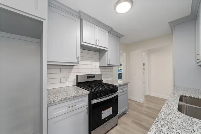 a kitchen with granite countertop stainless steel appliances a stove cabinets and wooden floor