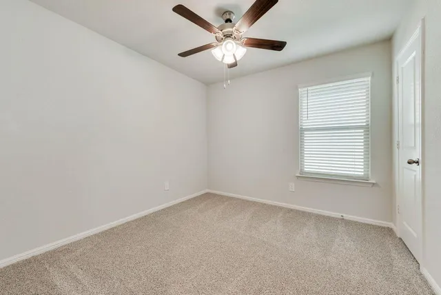 an empty room with a window and a ceiling fan