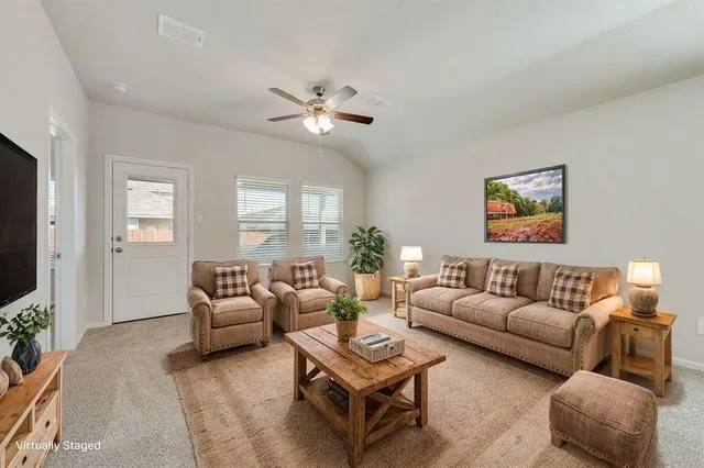 a living room with furniture a ceiling fan a lamp and a window