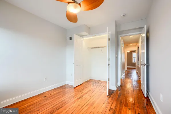 a view of a room with wooden floor and a ceiling fan