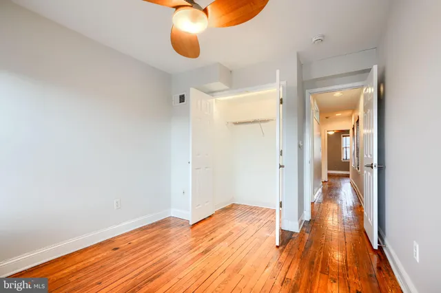 a view of a room with wooden floor and a ceiling fan