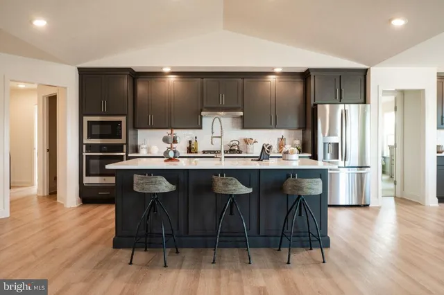 a kitchen with kitchen island granite countertop wooden floors cabinets and stainless steel appliances