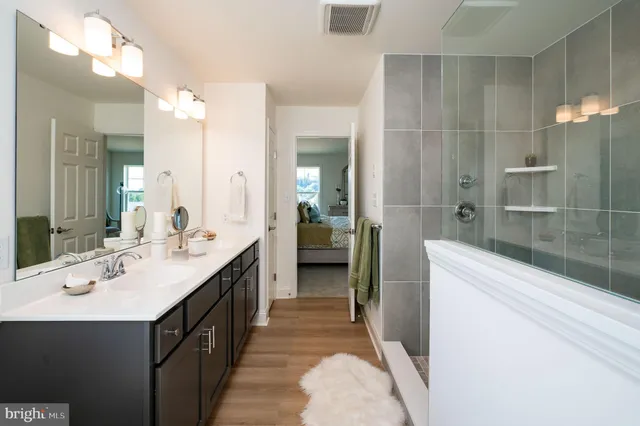 a bathroom with a double vanity sink a toilet and shower
