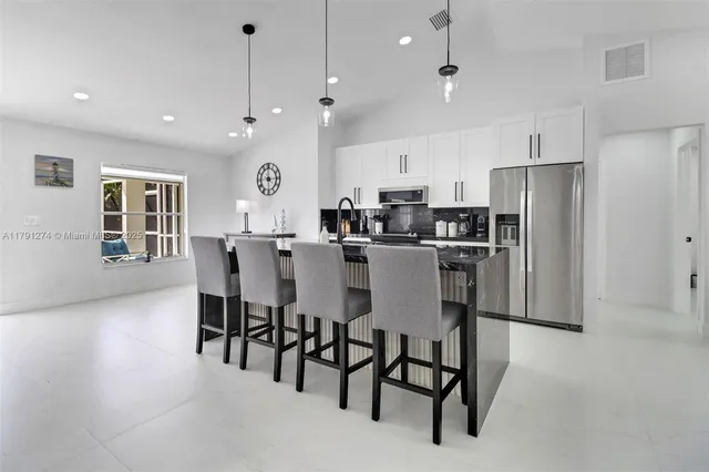 a kitchen with stainless steel appliances a dining table chairs refrigerator and microwave