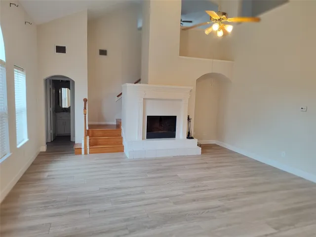 a view of an empty room with wooden floor and a fireplace