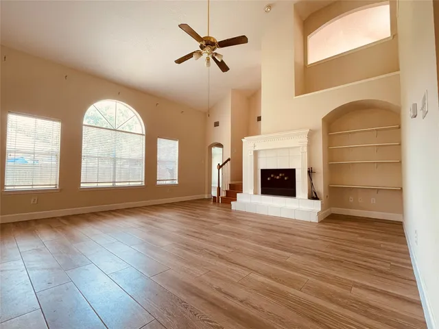 an empty room with wooden floor fireplace and windows