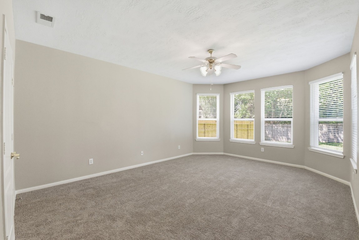 3414 Hackberry Court Spring, TX 77388 - Photo 22 of 50 The primary bedroom is downstairs and has so many beautiful windows letting in all the natural light! Notice the carpet that was replaced in April 2026, the fresh paint, the ceiling fan and the white faux wood blinds.