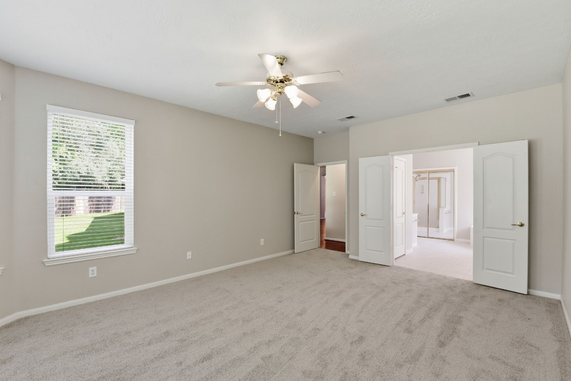 3414 Hackberry Court Spring, TX 77388 - Photo 24 of 50 The primary bedroom with recently replaced carpet, fresh paint and a ceiling fan has an ensuite bath with a double door entry.