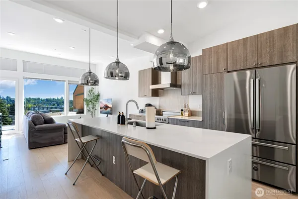 a kitchen with a refrigerator a stove a sink a dining table and chairs with wooden floor