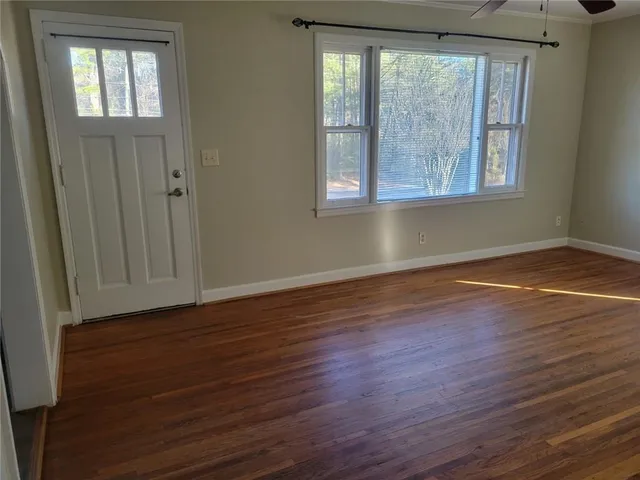 a view of an empty room with wooden floor and a window