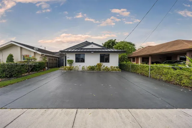 a front view of a house with a yard and potted plants