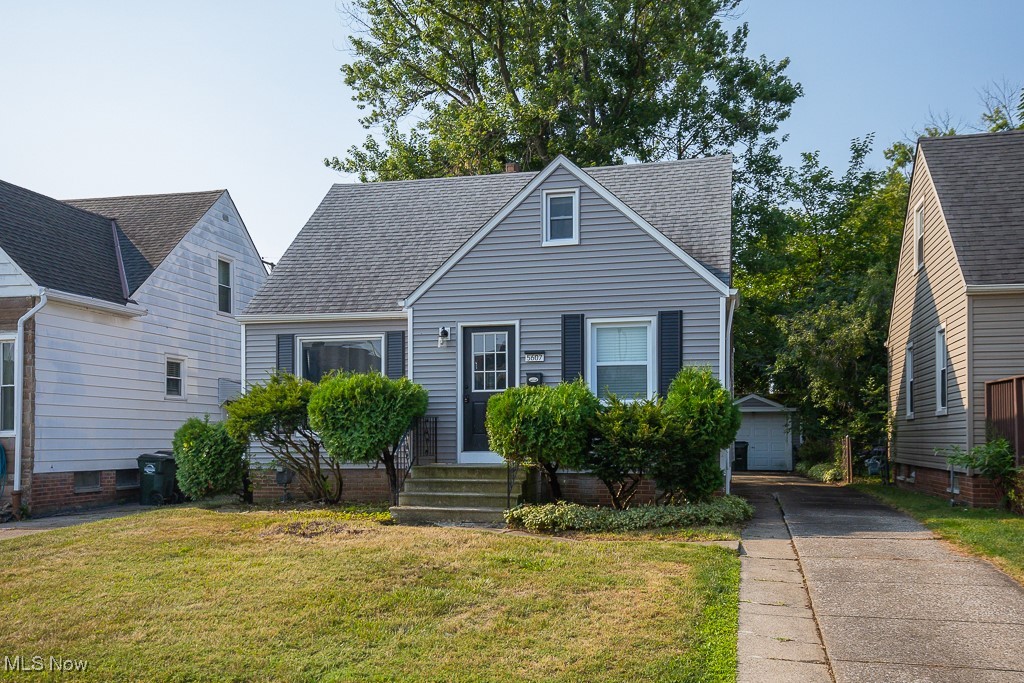 View of front of house featuring a garage, an outbuilding, and a front yard
