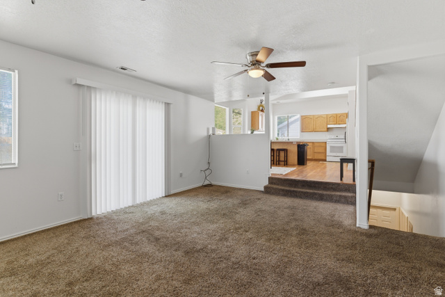 134 West 475 South Ogden, UT 84404 - Photo 8 of 27 Unfurnished living room featuring ceiling fan, carpet, and a textured ceiling