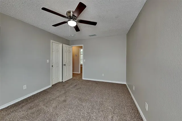 an empty room with ceiling fan and window