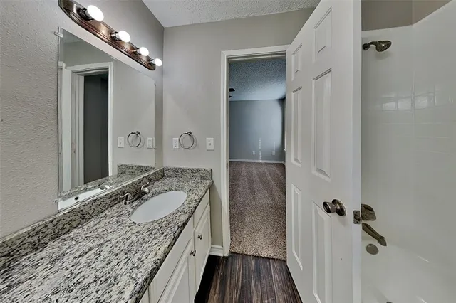 a bathroom with a granite countertop sink a mirror and shower